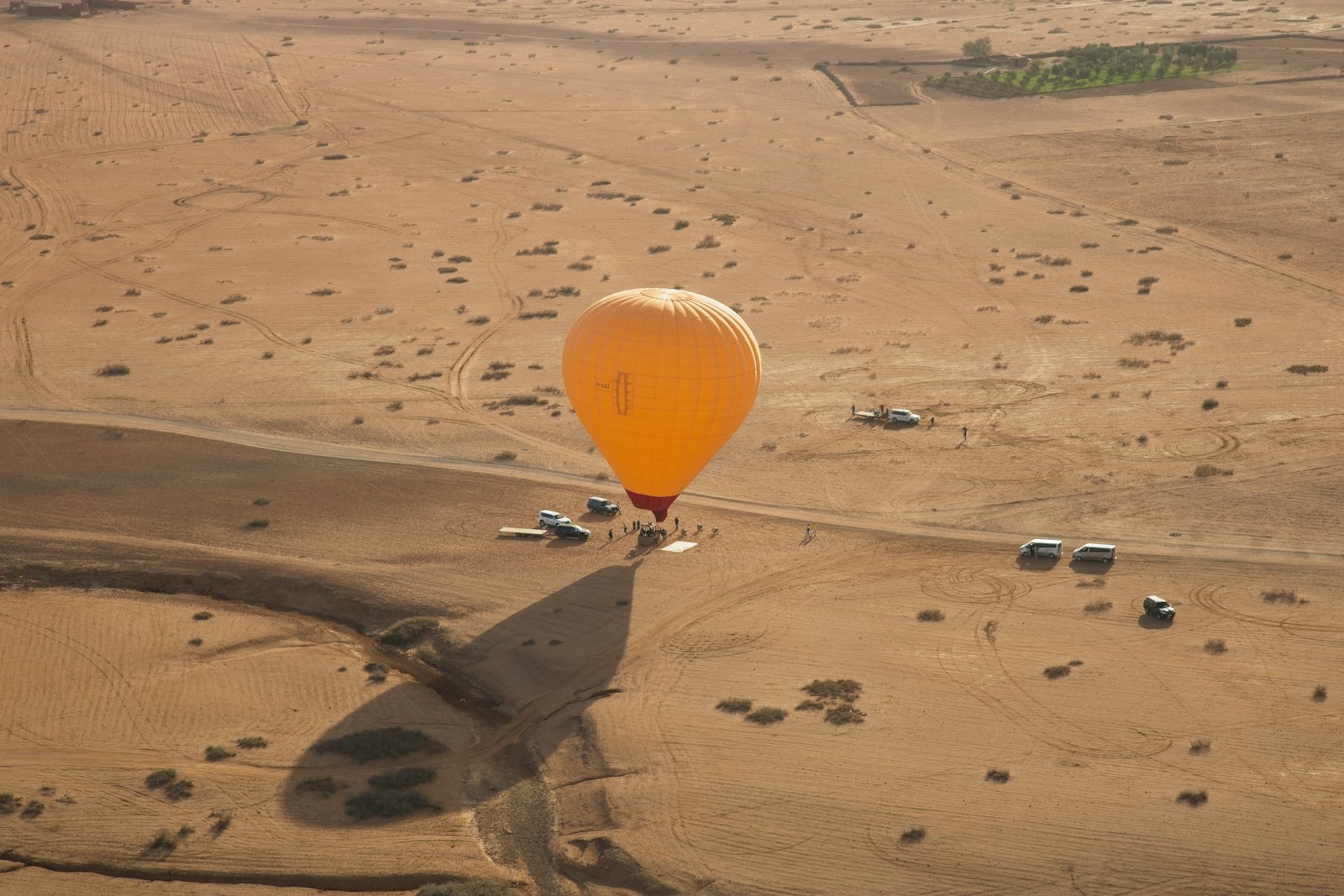 An orange hot air balloon soars above the desert.
