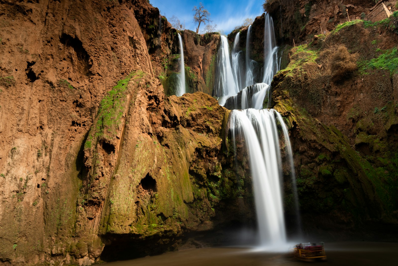 a boat is in the water near a waterfall